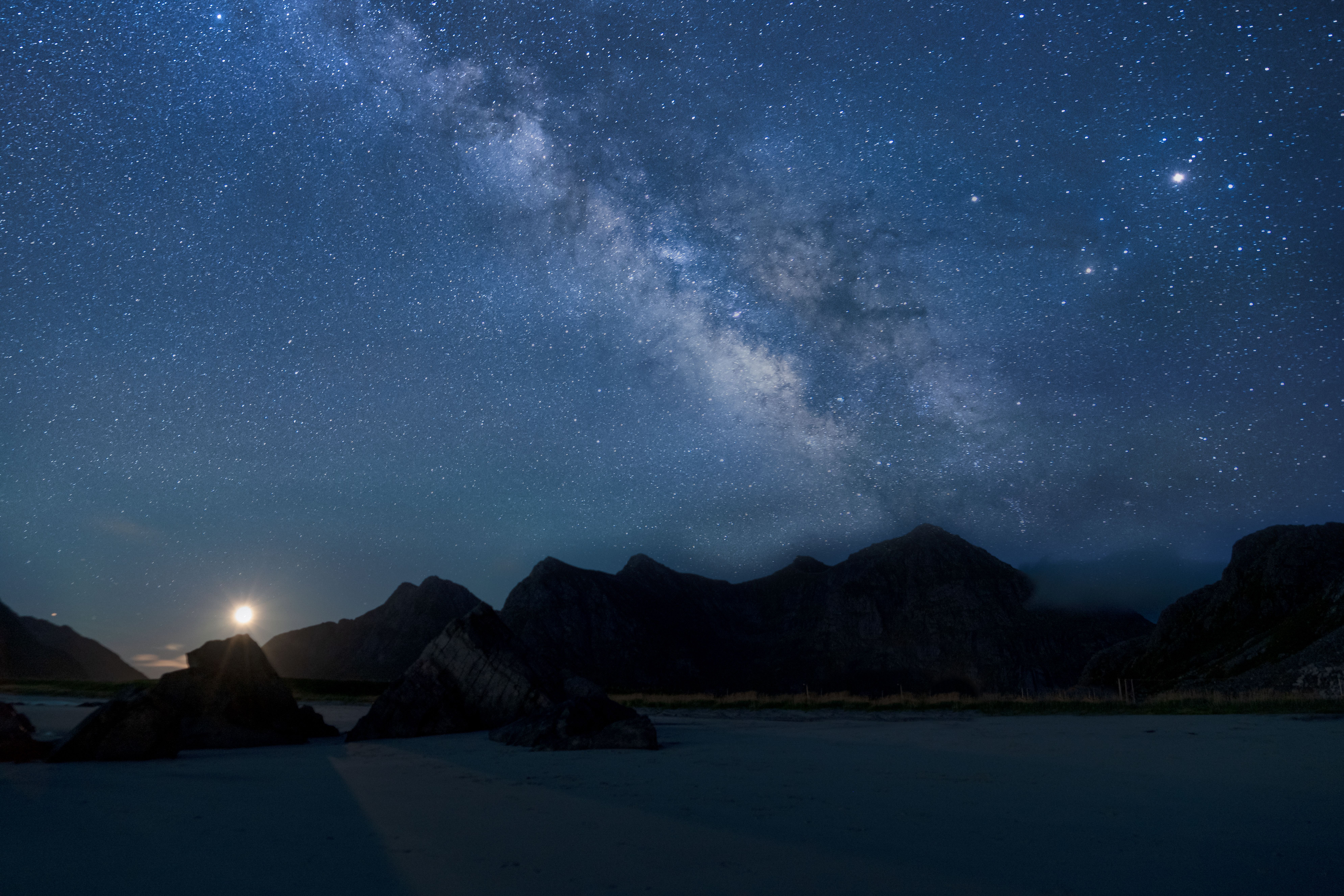 夜间，从山脉轮廓和湖泊上方俯瞰，银河系的景色令人惊叹