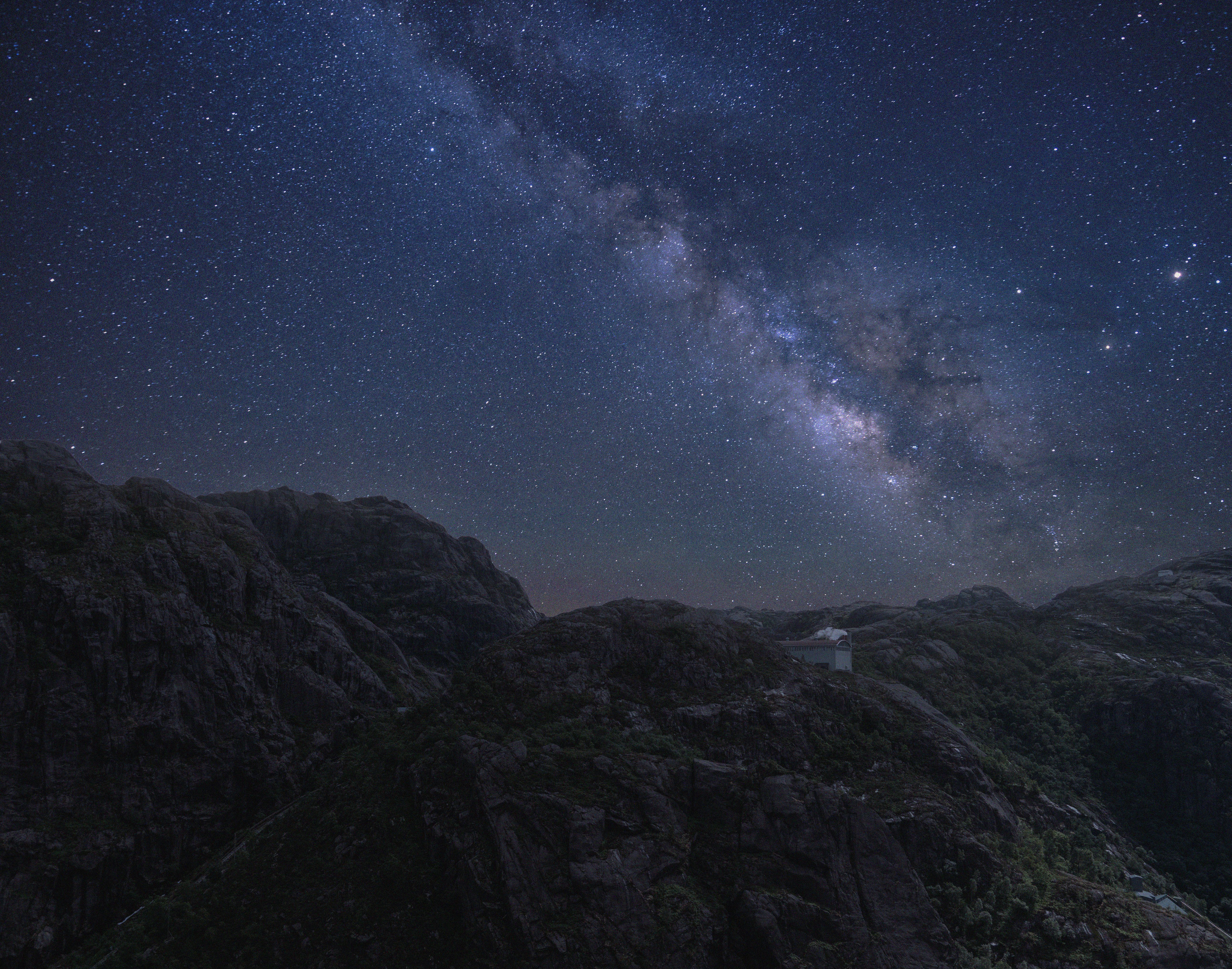 在黑暗的夜空中，明亮的星星在高耸的岩石山区闪耀