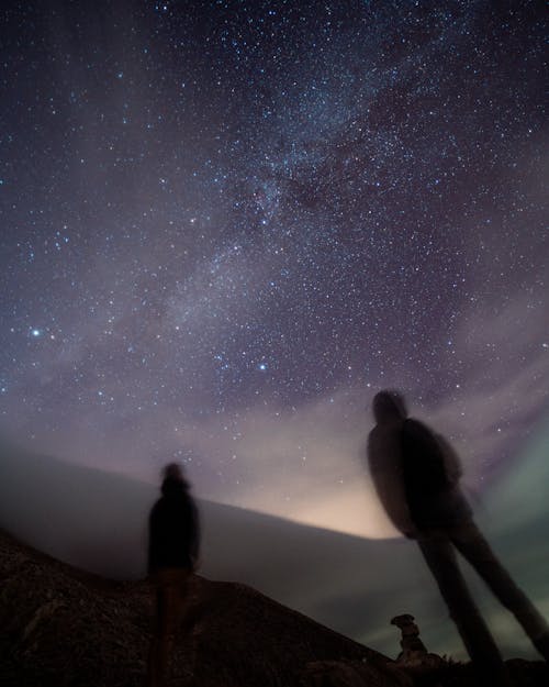 Silhouette of Two People Standing Under a Starry Night Sky