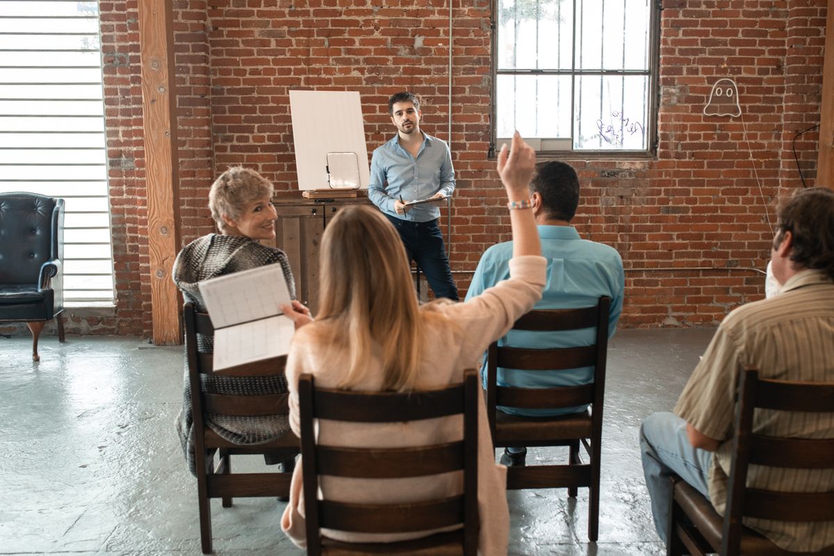 Groupe d'adultes en action de formation échangeant avec un intervenant