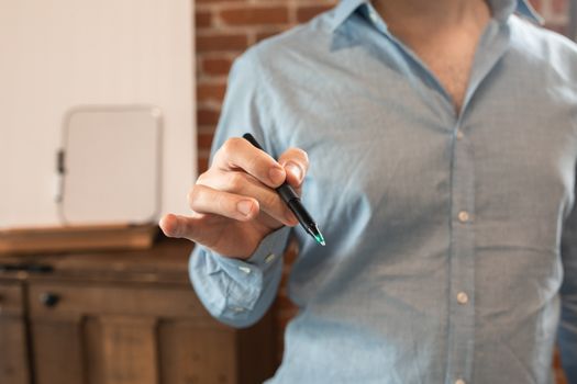 室内特写：一名穿蓝色衬衫的男子手持笔，非常适合商业概念