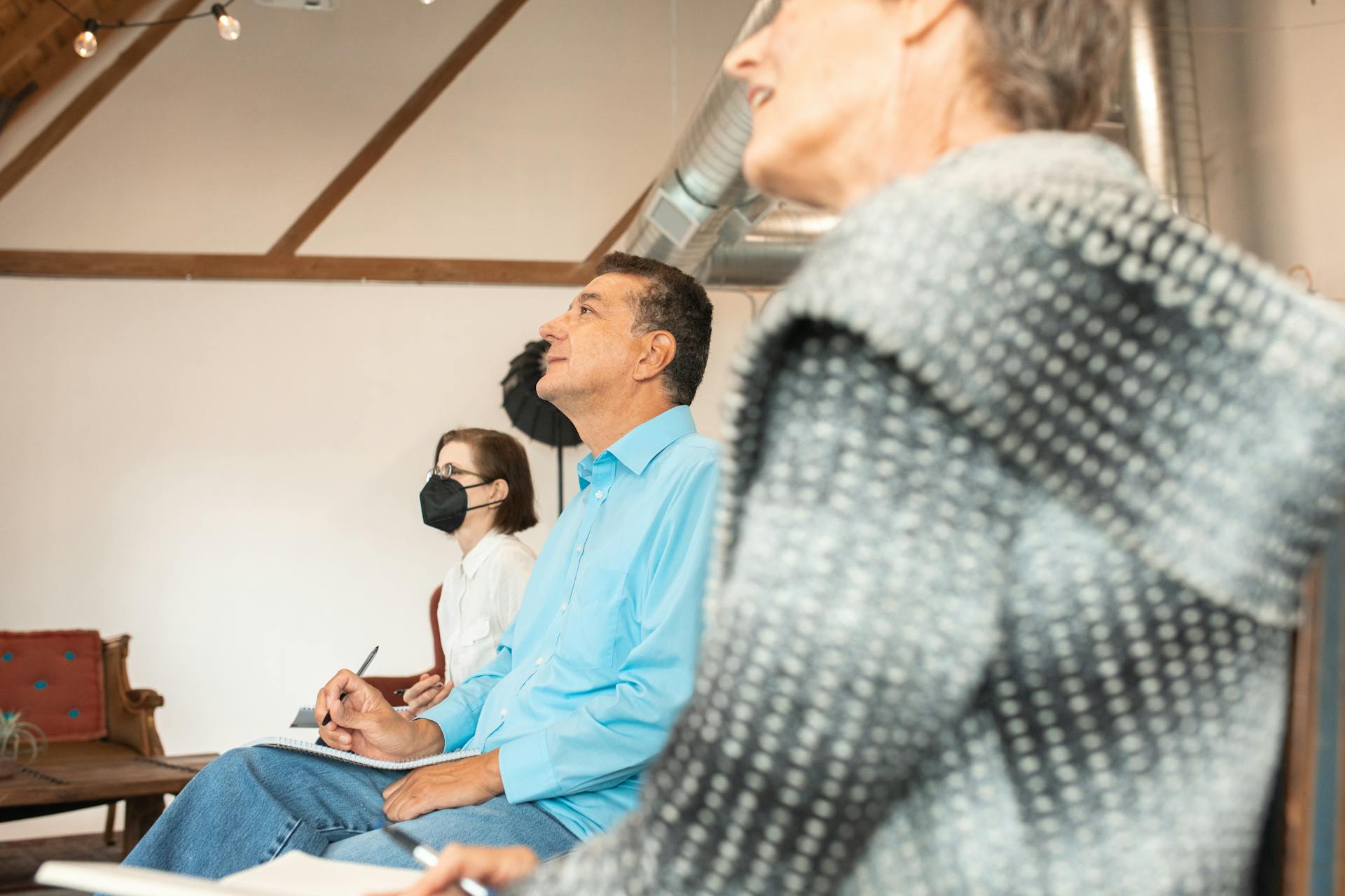 Adults attentively participate in an educational workshop, taking notes.