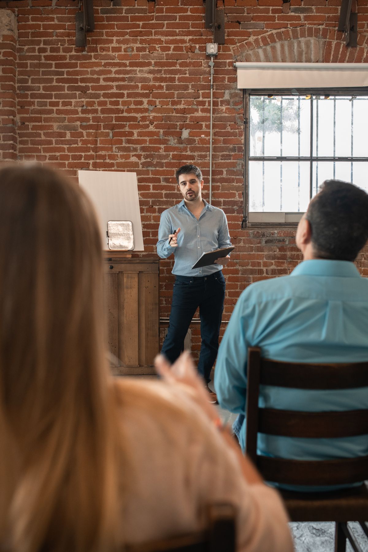 A facilitator speaking with a small group in a brick-walled studio