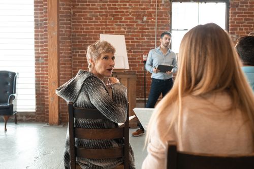 Free Group of adults engaged in a seminar in a rustic setting with brick walls and wooden chairs. Stock Photo