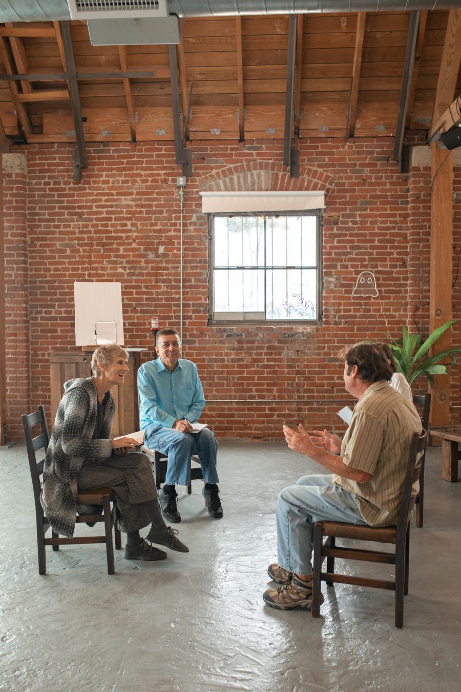 Adults seated in a semicircle in a community room, taking part in a facilitated group discussion.