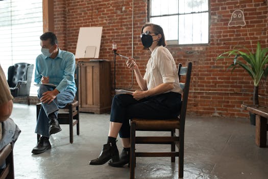 Adults in a classroom setting geared up with masks, engaging in a group learning discussion.