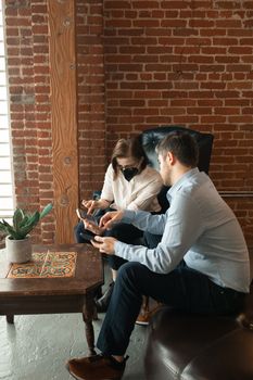 Two people using smartphones in a stylish indoor setting with brick walls.