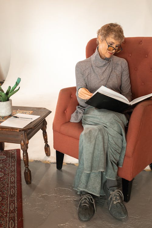 A Woman Sitting on an Armchair Reading a Book