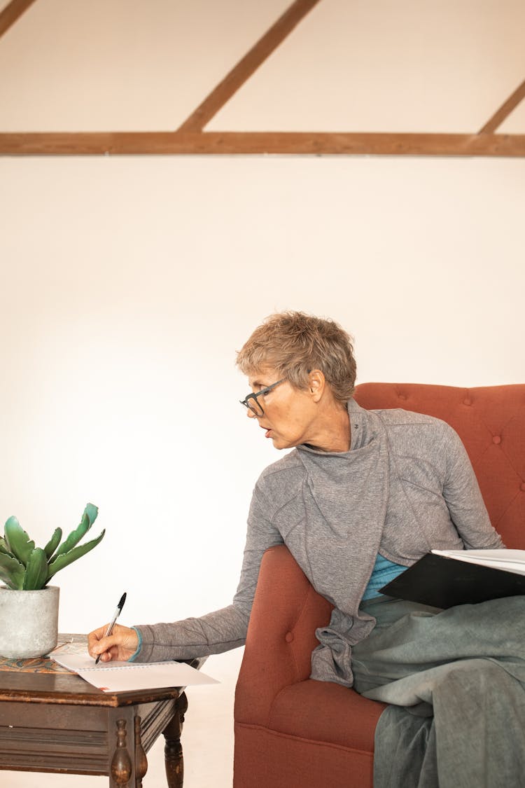 Woman Writing On A Paper On The Side Table