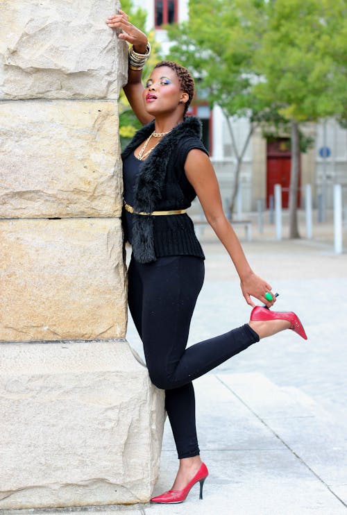 Free Woman in Black Tank Top and Black Leggings Leaning on Concrete Wall Stock Photo