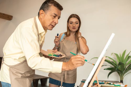  A Man and a Woman Painting on a Canvas