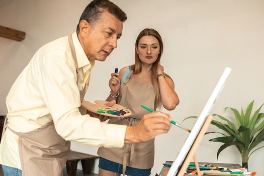 Adult students painting in an art studio, focused on creativity and learning.