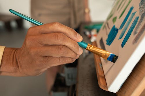 Person Holding Blue and Brown Paint Brush