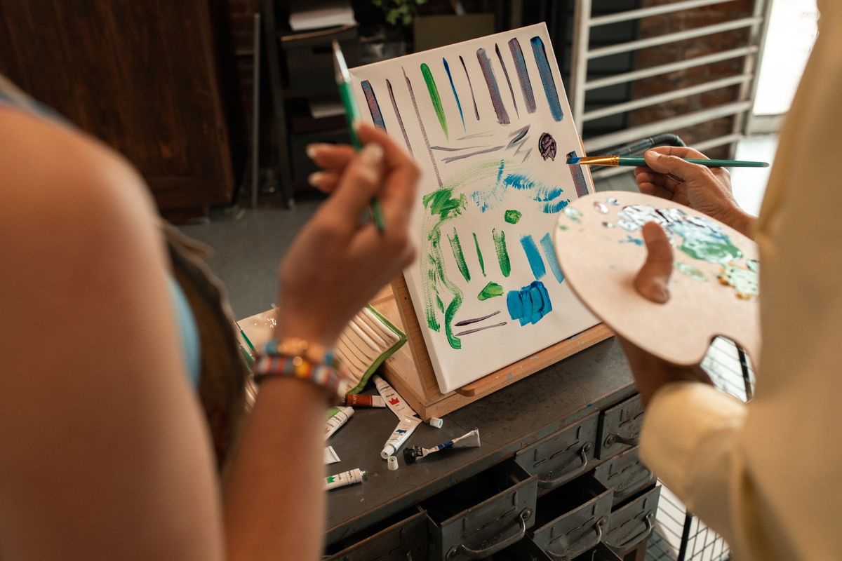 Hands creating art in therapeutic setting with painting supplies