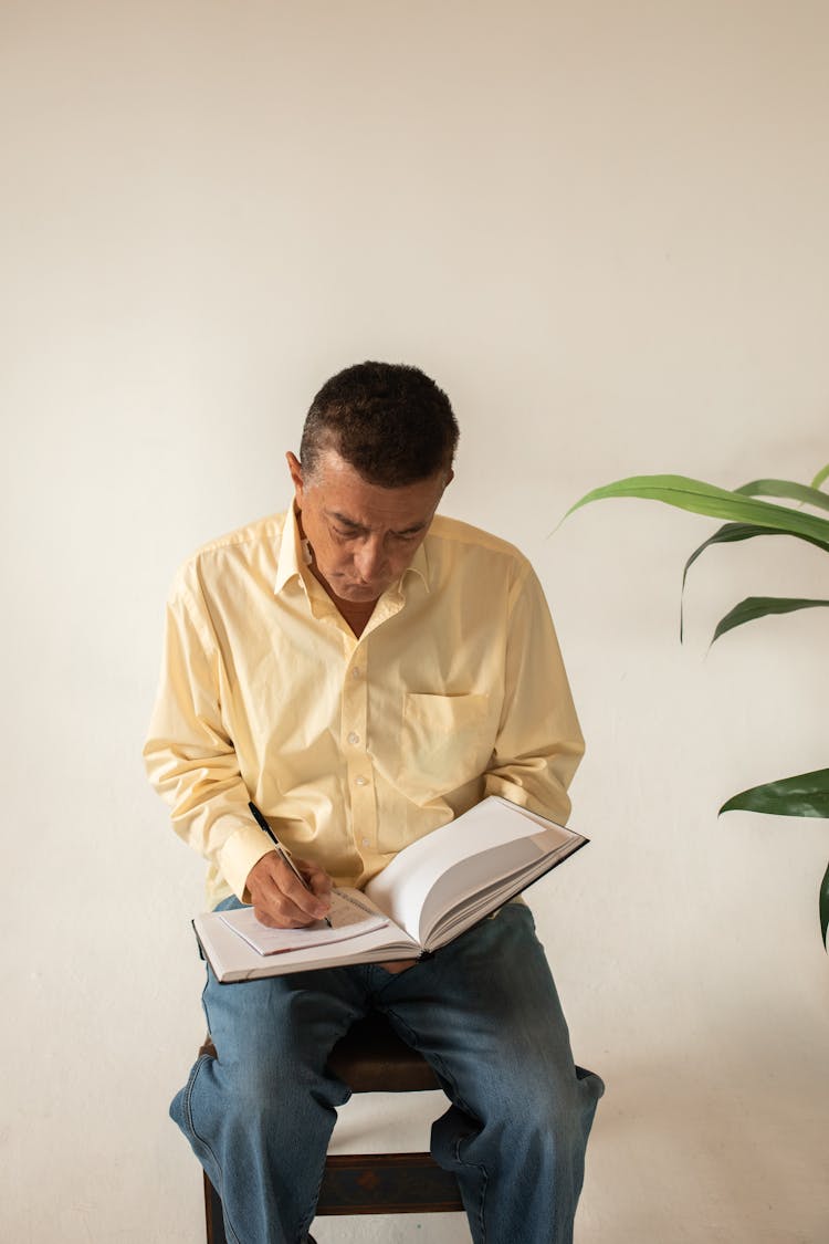 A N Elderly Man Writing Notes While Reading A Book