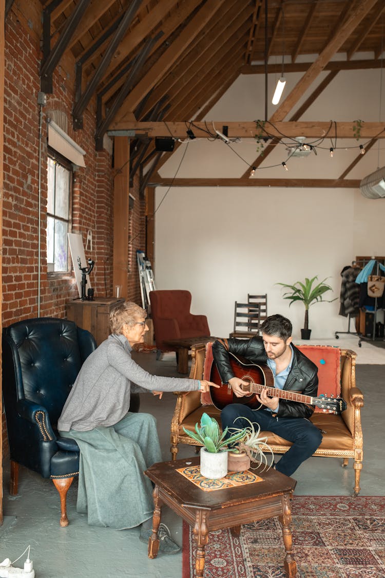 A Woman Teaching A Man To Play The Guita