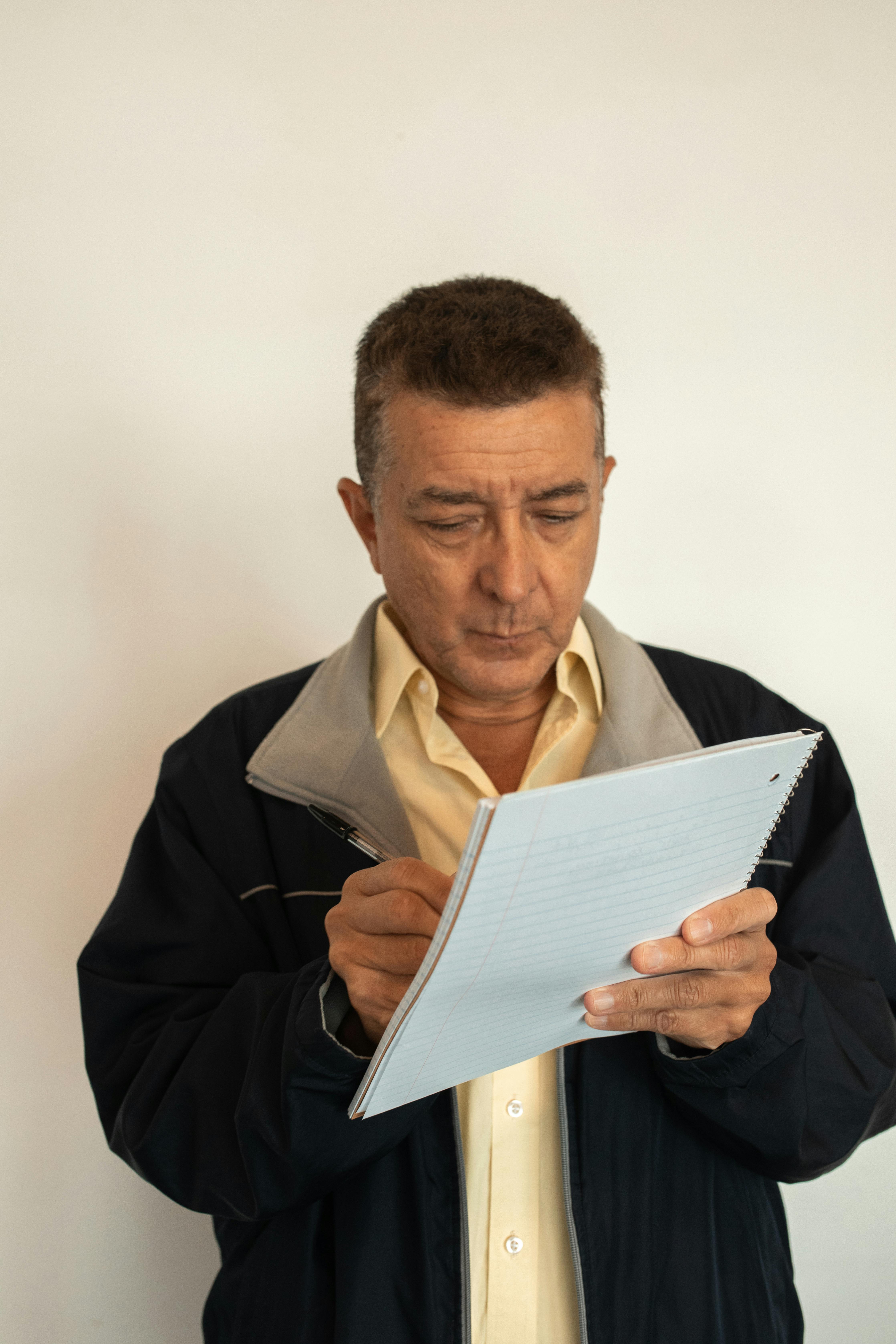 man in black jacket holding white paper