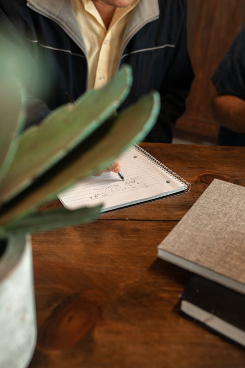 A Person Writing on White Notebook