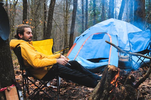 A Man Sitting on Camping Chair Near Tent