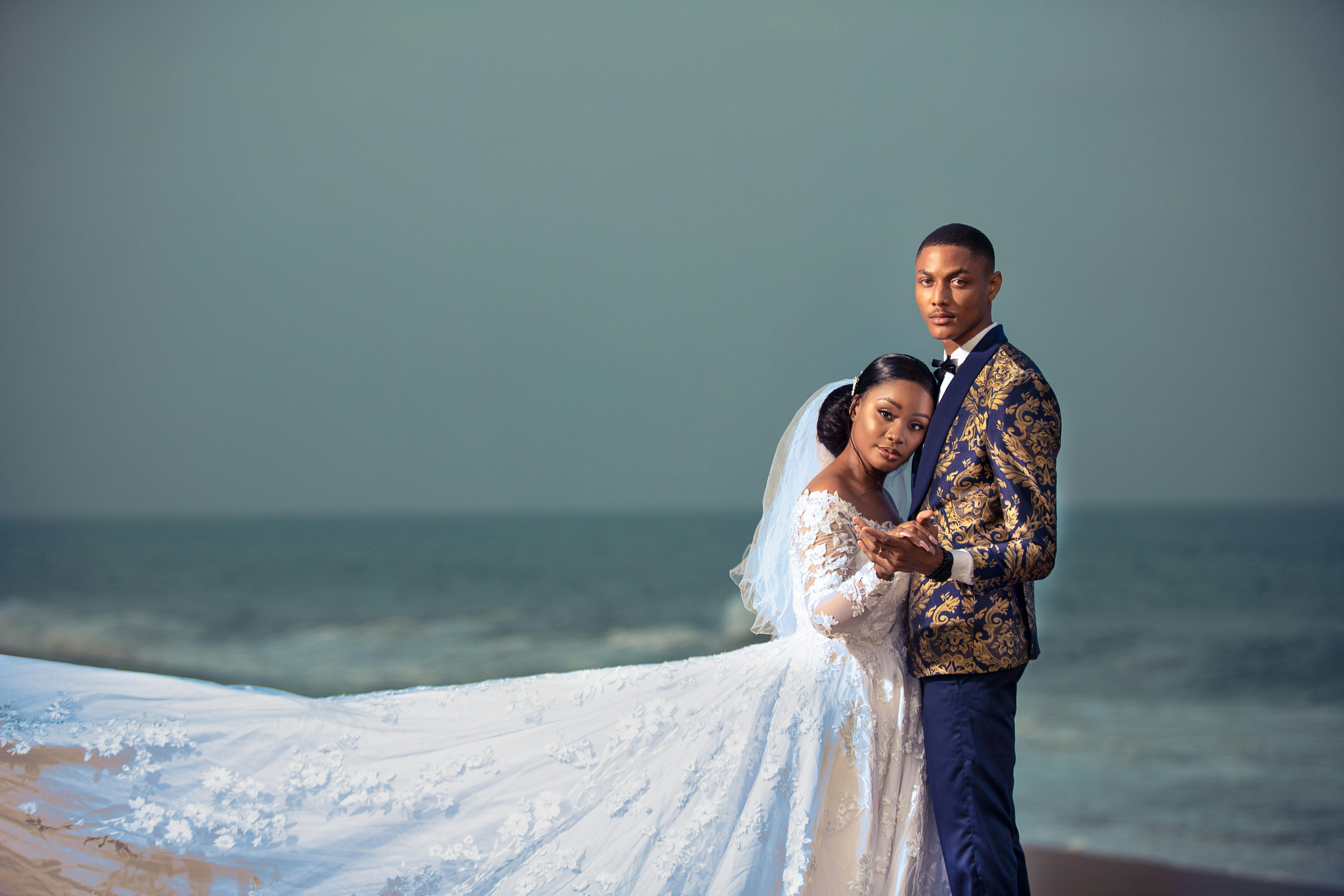 A couple embraces on a beach in Togo, showcasing elegant wedding attire.