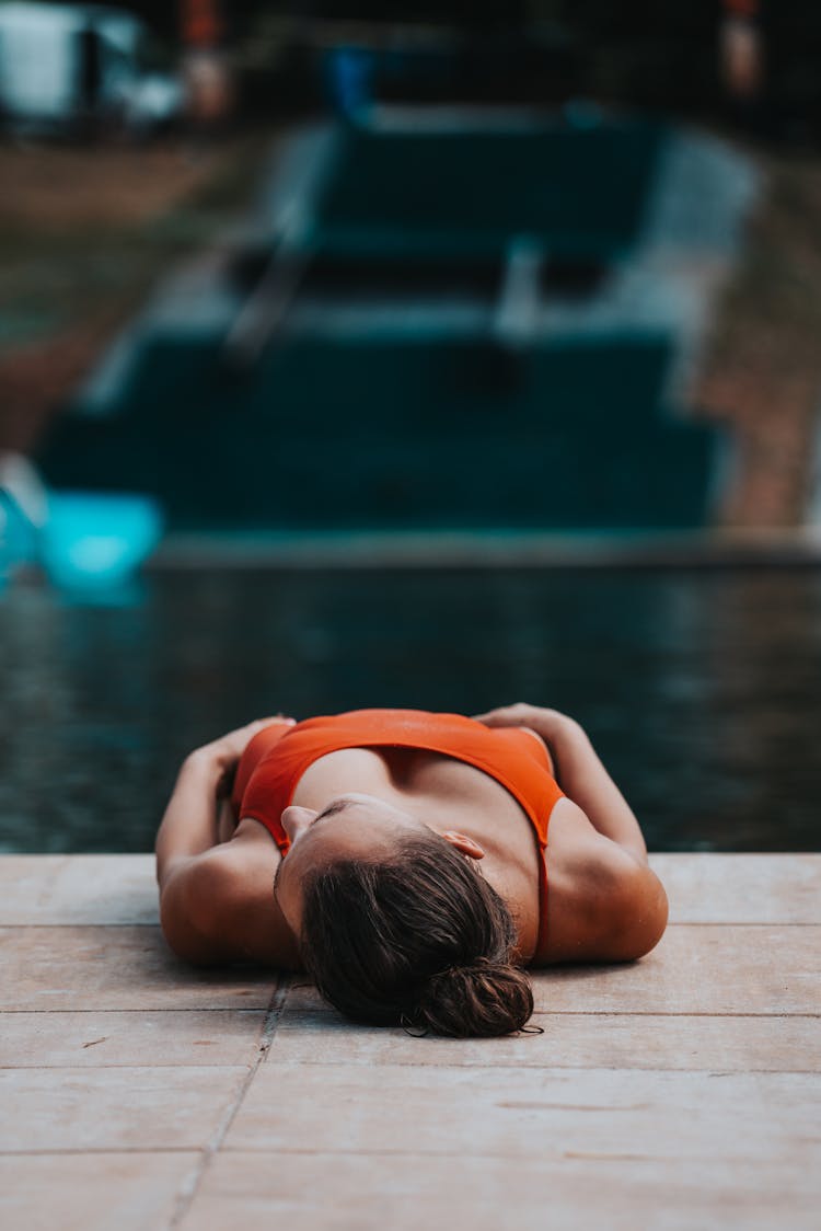 A Woman Lying On Brown Wooden Pool Deck