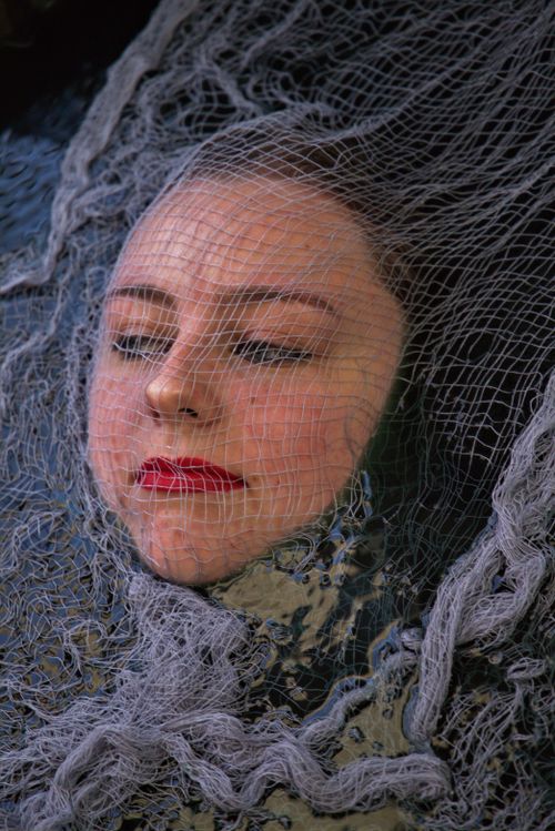 Free A dramatic portrait of a woman with red lips under a delicate mesh, conveying a mysterious mood. Stock Photo