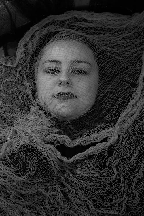 Grayscale Photo of Woman's Face Covered with Mesh Fabric