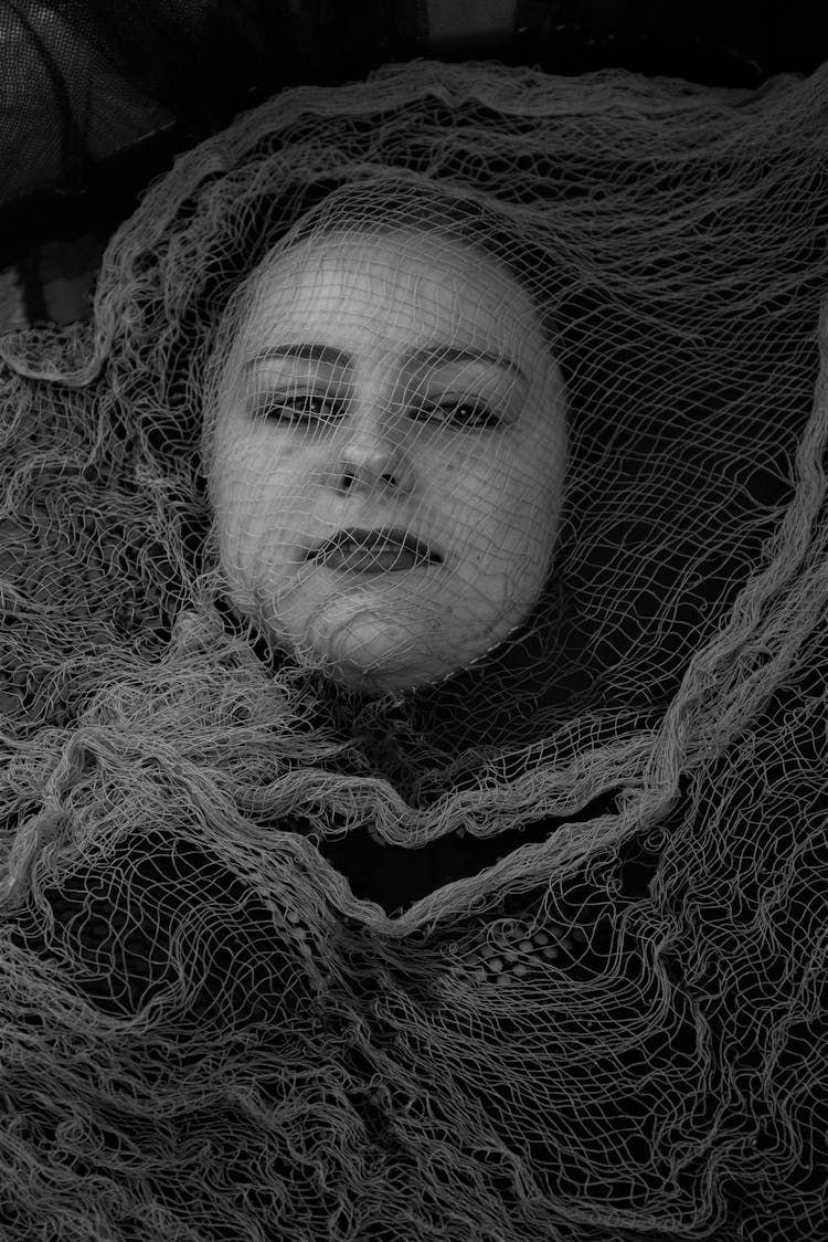 Grayscale Photo Of Woman's Face Covered With Mesh Fabric