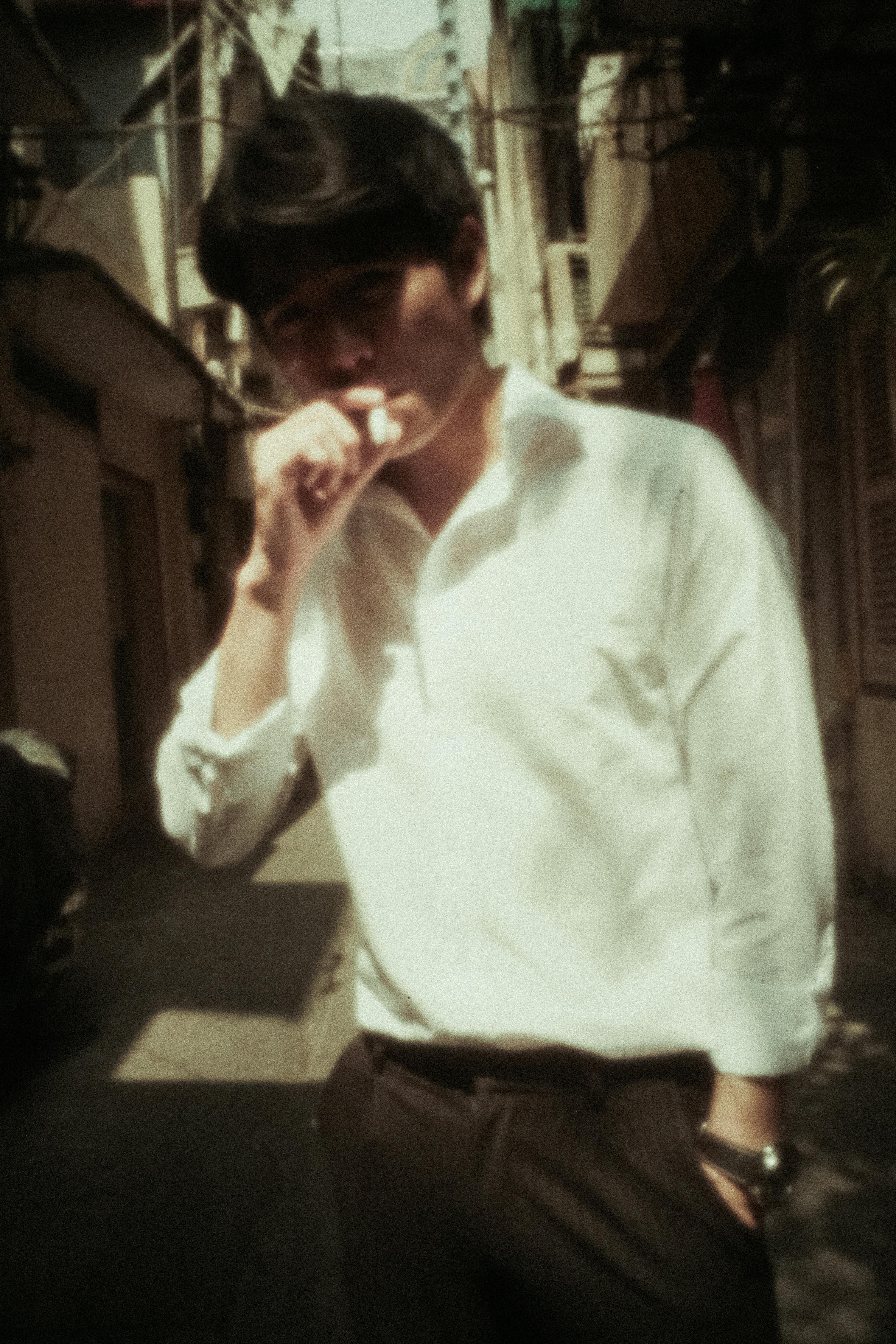 relaxed young asian guy smoking cigarette in city