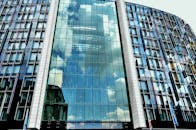 一座现代摩天大楼的玻璃立面，映照着蓝天和云层