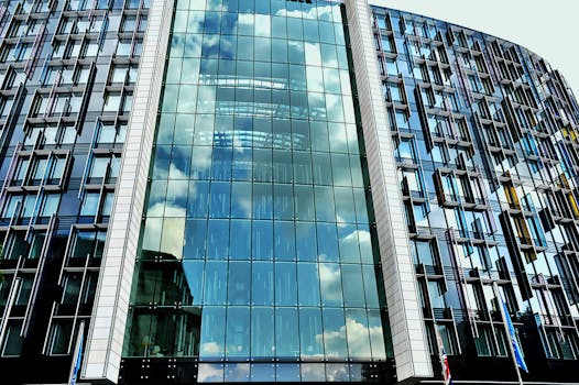 一座现代摩天大楼的玻璃立面，映照着蓝天和云层