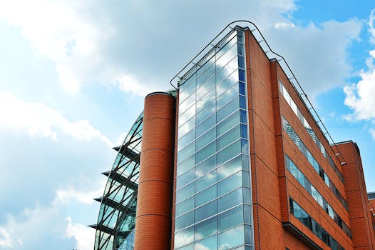 一座高大的现代建筑，玻璃窗映照着天空，展现出城市的建筑风貌