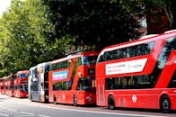 伦敦街道的绿树下停着一排传统的红色双层巴士