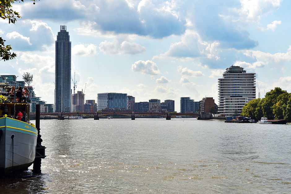 Scenic view of London's skyline featuring skyscrapers and the River Thames under a cloudy sky.