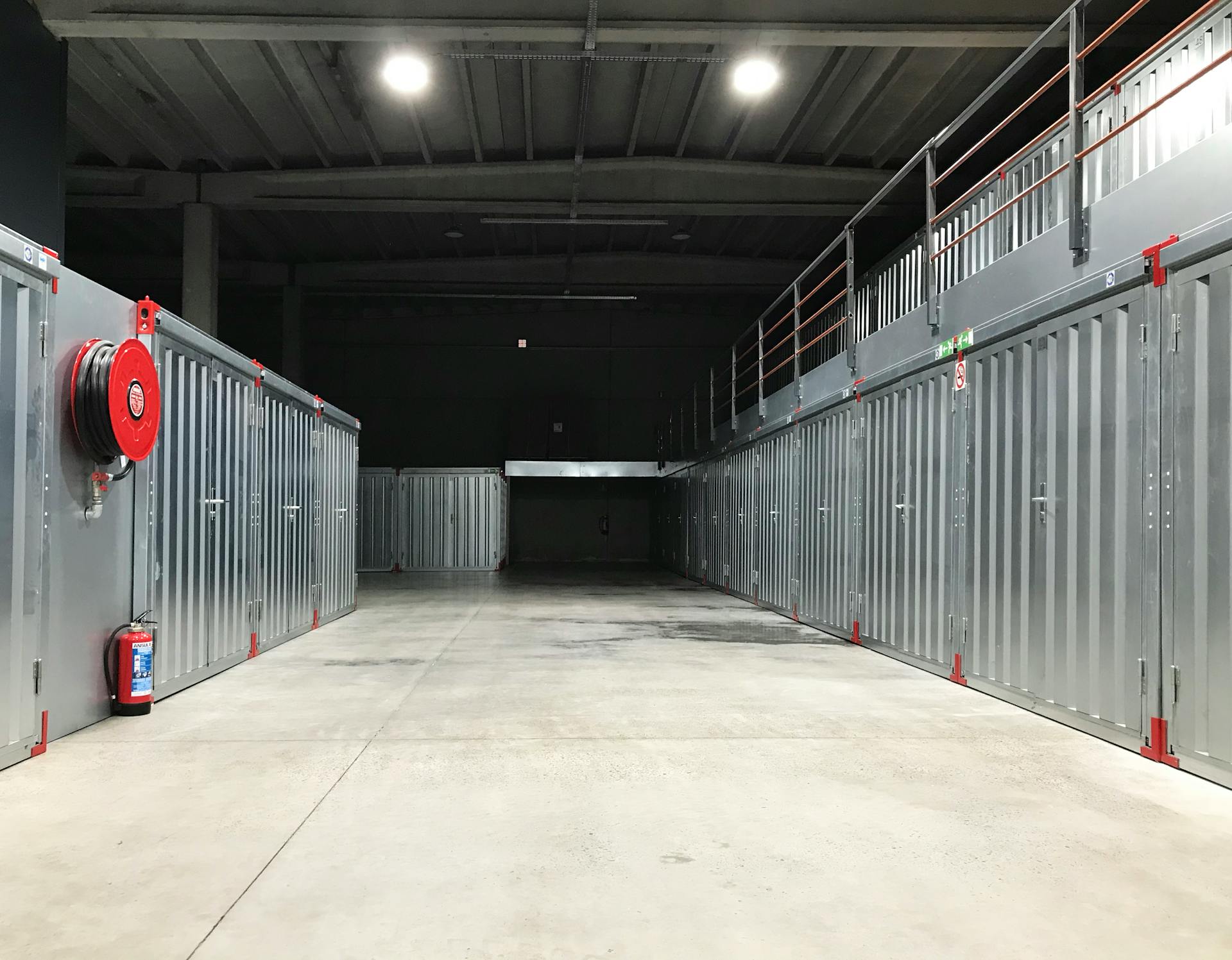 Spacious industrial warehouse interior featuring steel storage units and safety equipment.