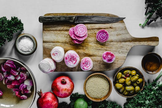 Top view of colorful chioggia beets on a wooden cutting board, surrounded by healthy ingredients like kale and olives.