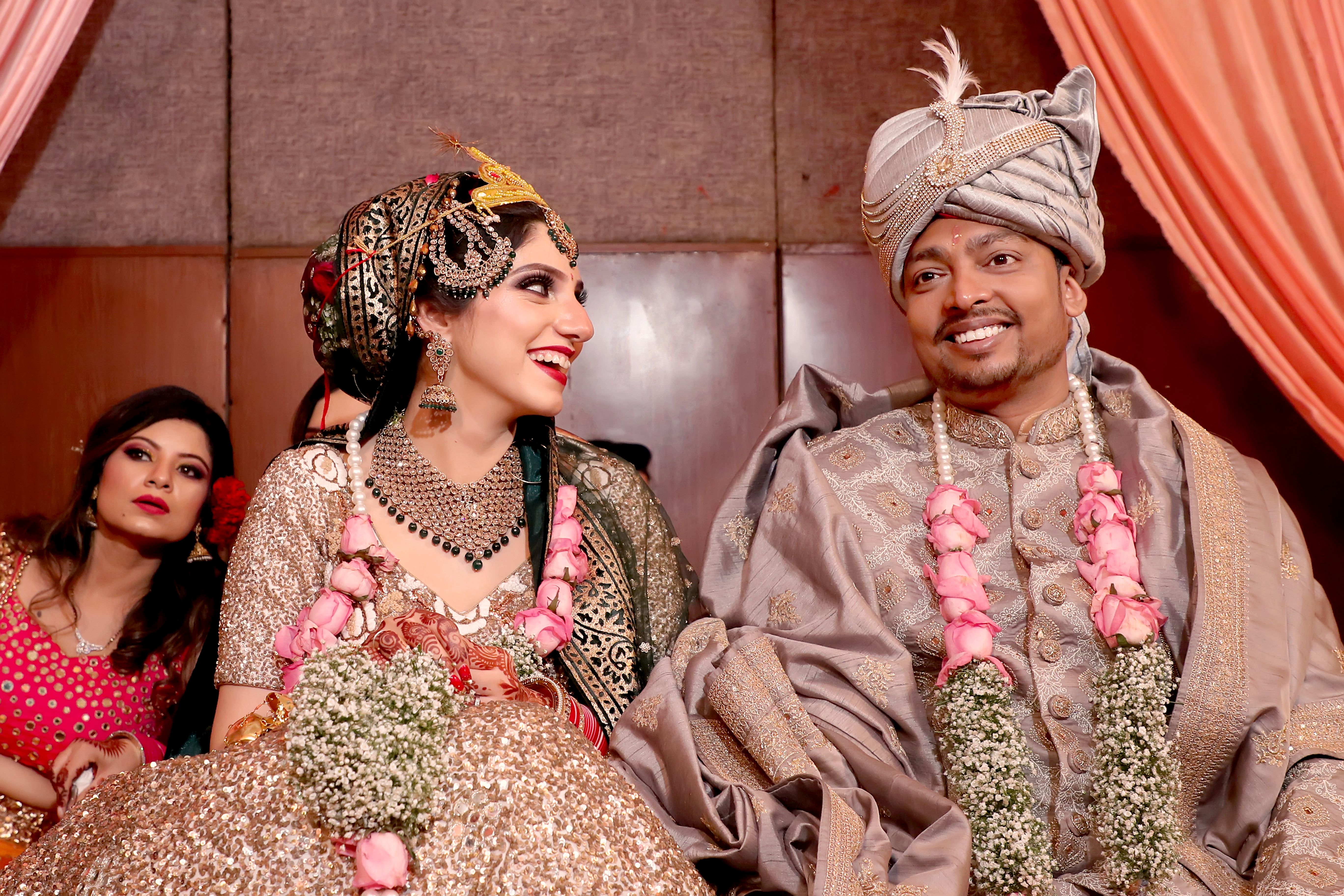 A joyful Indian bride and groom in traditional attire during their wedding ceremony indoors.