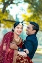 Happy Indian couple laughing in traditional attire outdoors.