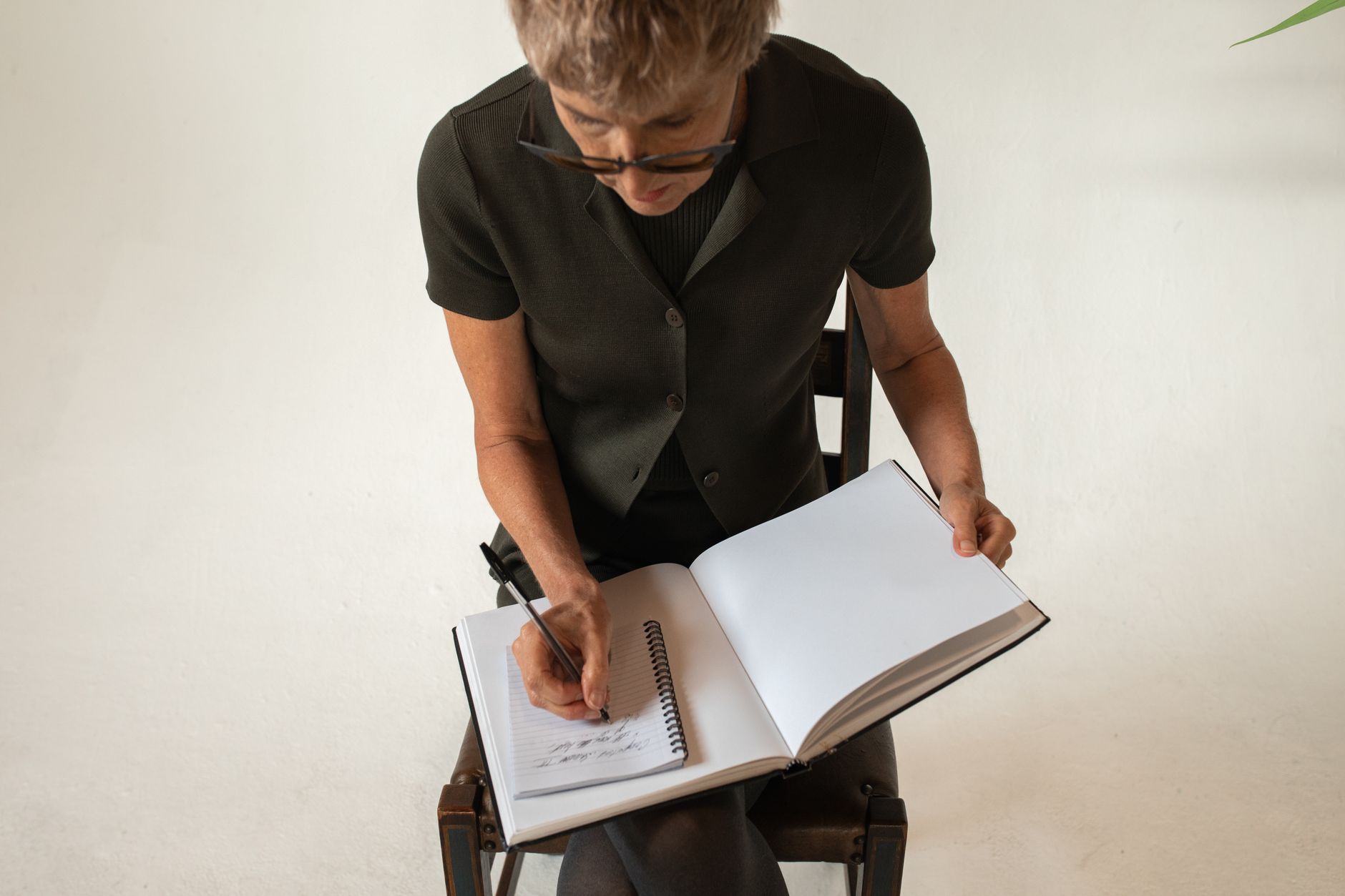 Senior adult woman writing in a notebook indoors, focusing on learning and education.