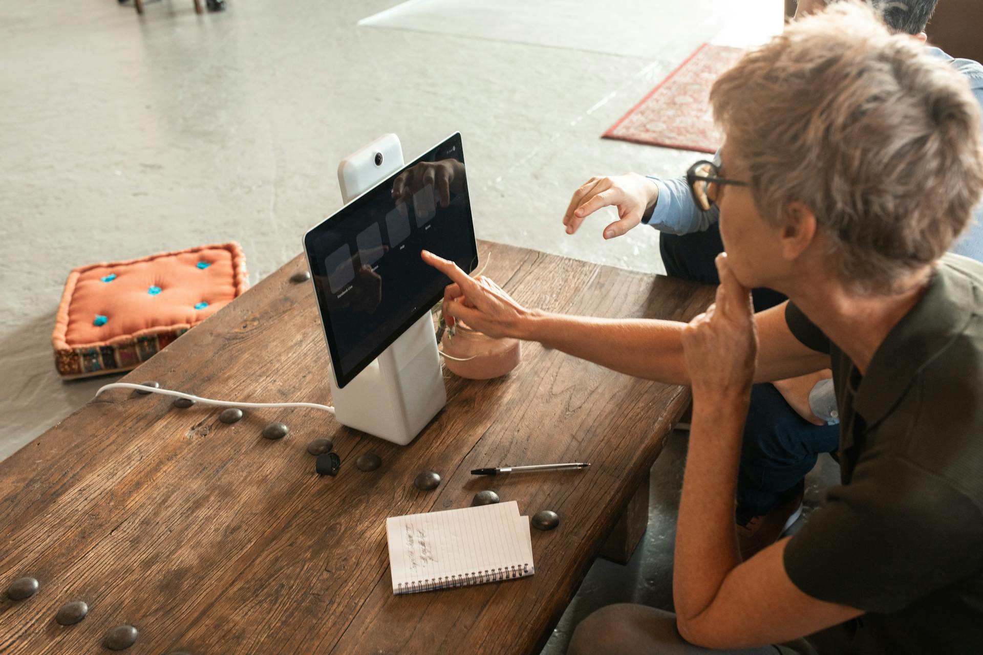 Elderly woman engaged in online learning via a digital tablet indoors.