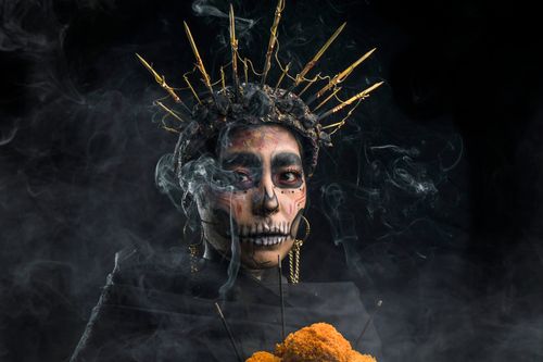 Free Dramatic portrait of a woman in traditional Day of the Dead makeup surrounded by smoke. Stock Photo