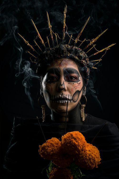 Free Striking portrait featuring Day of the Dead makeup with flowers and crown against black background. Stock Photo