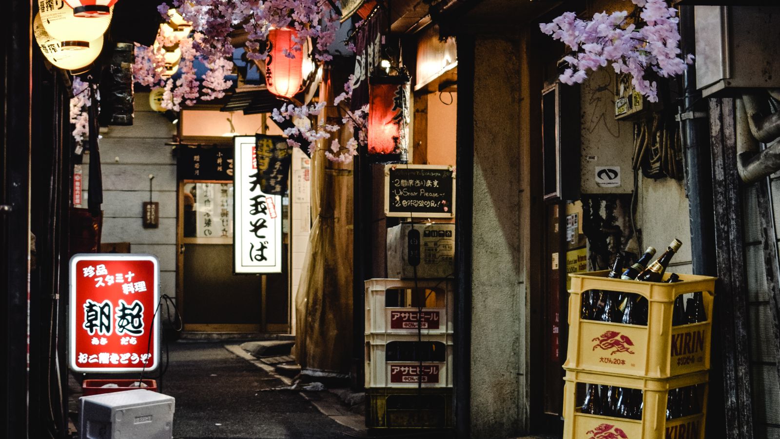 A narrow neon- and lantern-lit alley in Shinjuku, Tokyo at night with no people in the frame, a real stock photo chosen for the neon-soaked look of Night City in Cyberpunk: Edgerunners 2, an anime made by Japan's Trigger studio