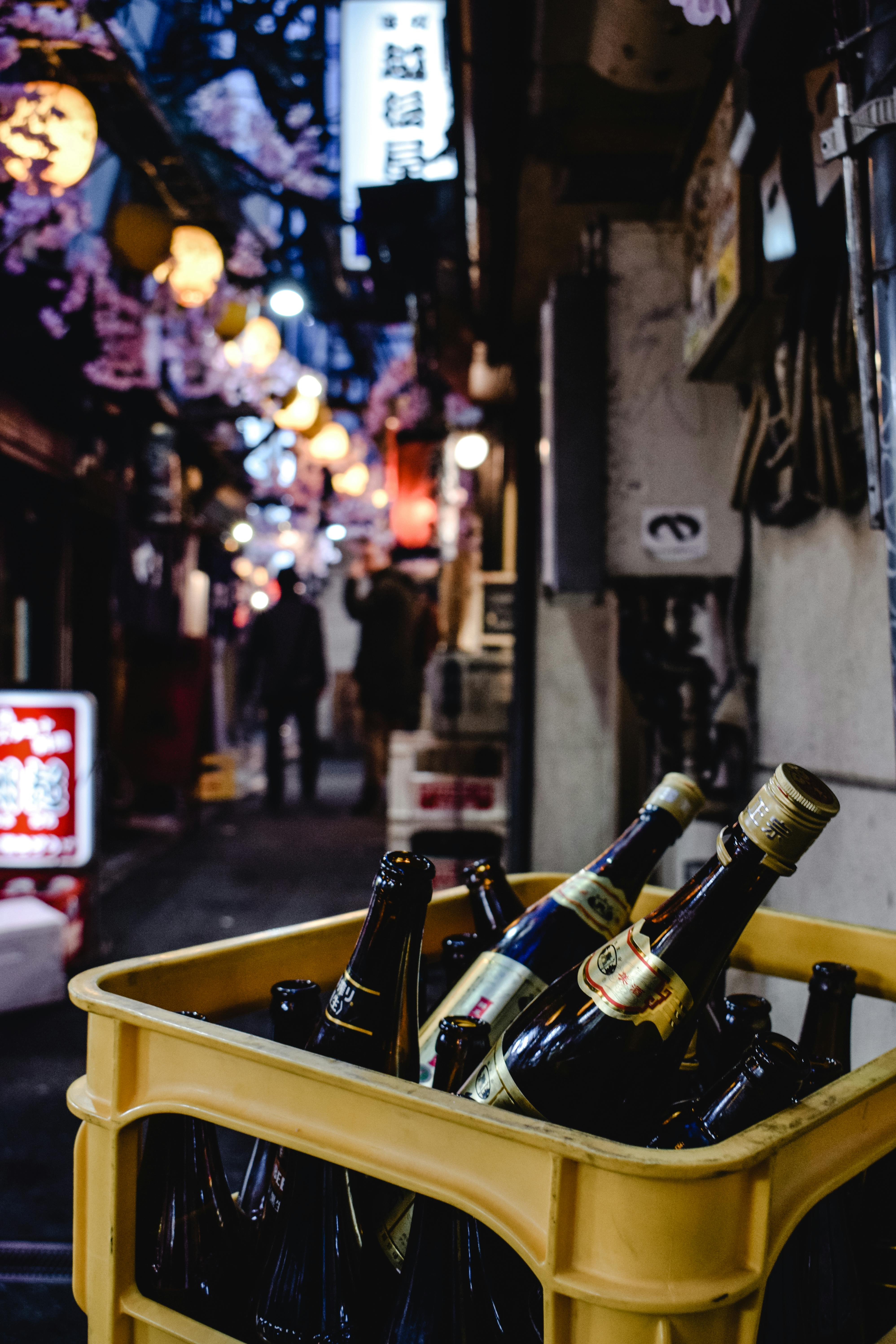 灯火通明的城市小巷里，板条箱中的啤酒瓶特写