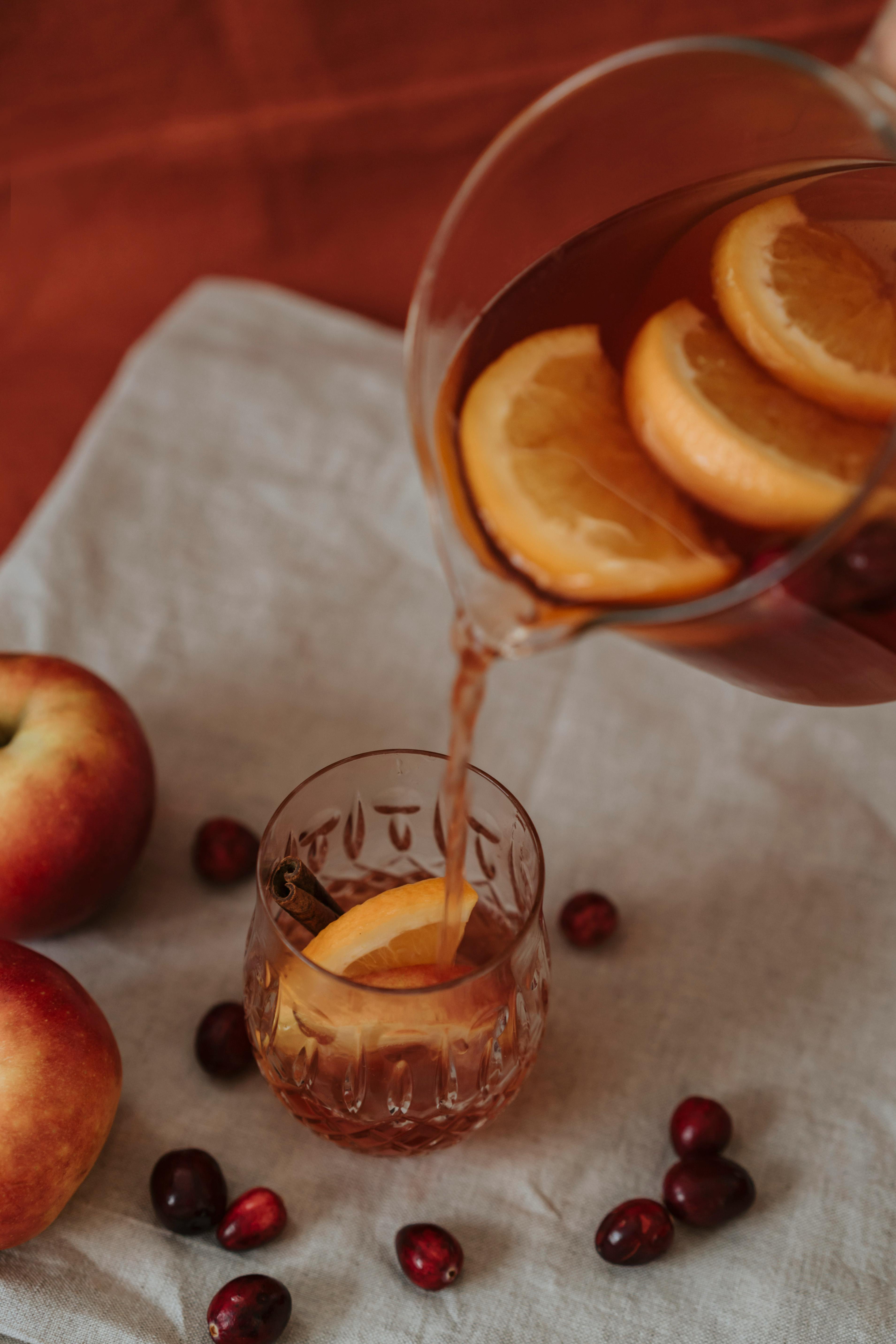 杯子里装满了柑橘苹果茶，周围摆放着水果，营造出舒适的静物氛围