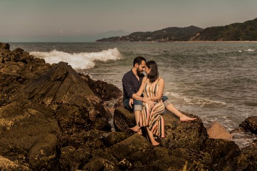Free A loving couple enjoys a serene moment sitting together on the rugged coastal rocks. Stock Photo