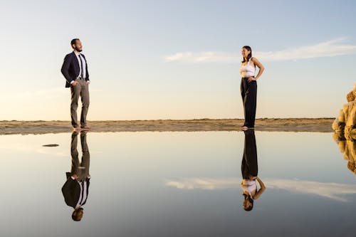 Man and Woman Holding Hands While Walking on Seashore