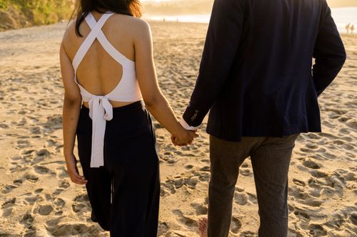 Free A romantic couple holding hands, walking on a sandy beach at sunset, symbolizing love and companionship. Stock Photo