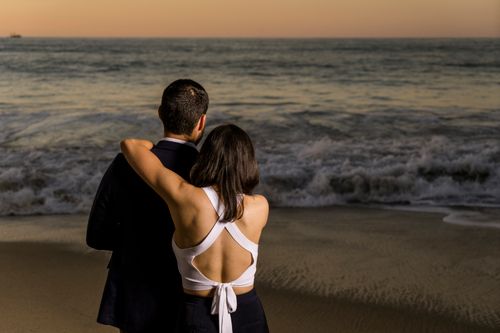 Free A couple embraces on the beach at sunset, enjoying the serene ocean view. Stock Photo