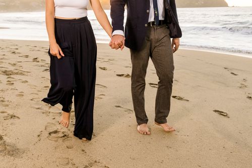Free Couple holding hands while walking barefoot on the beach, symbolizing romance and connection. Stock Photo